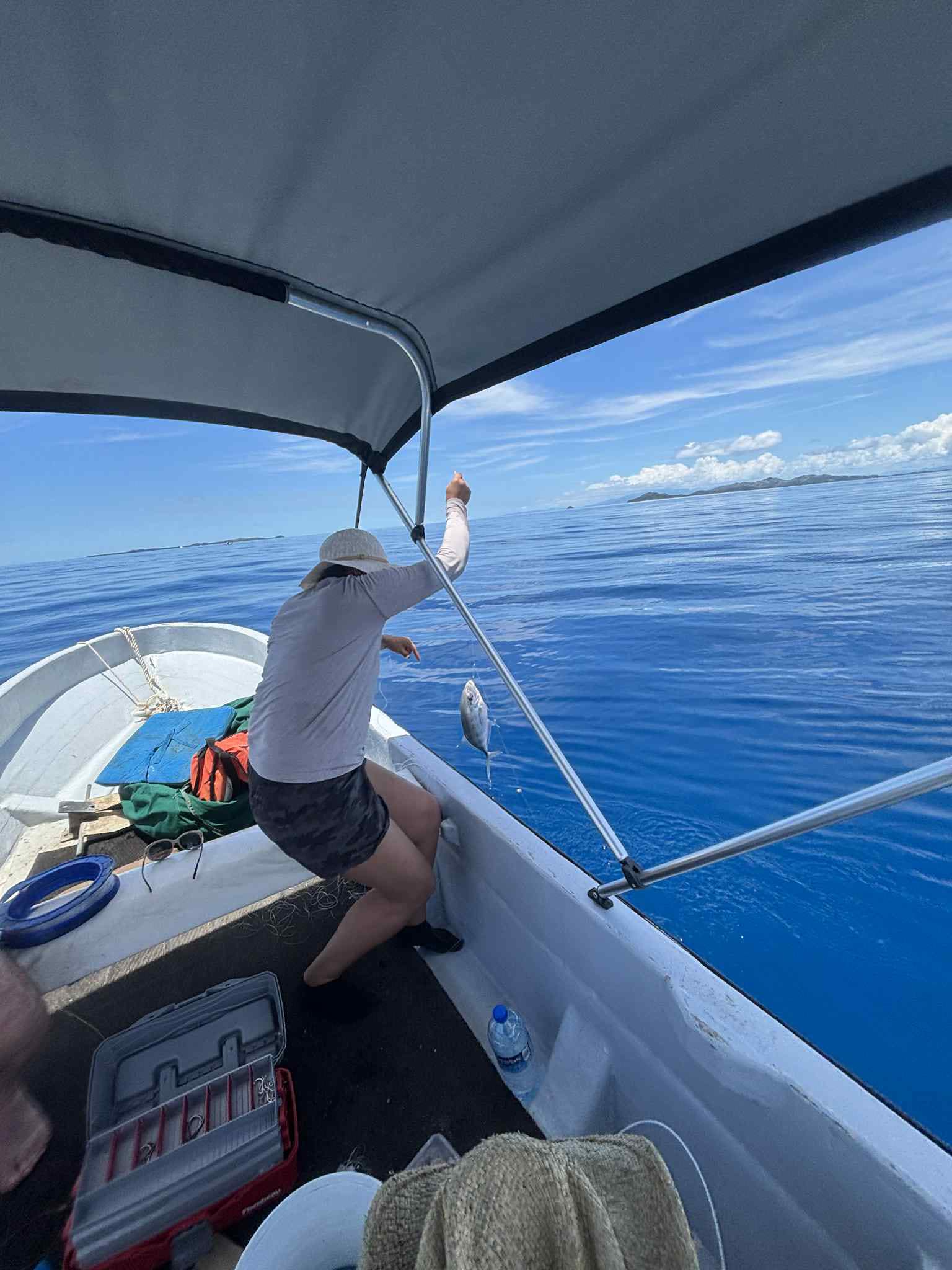 Reeling in a catch over calm, deep-blue open water near Mana Island